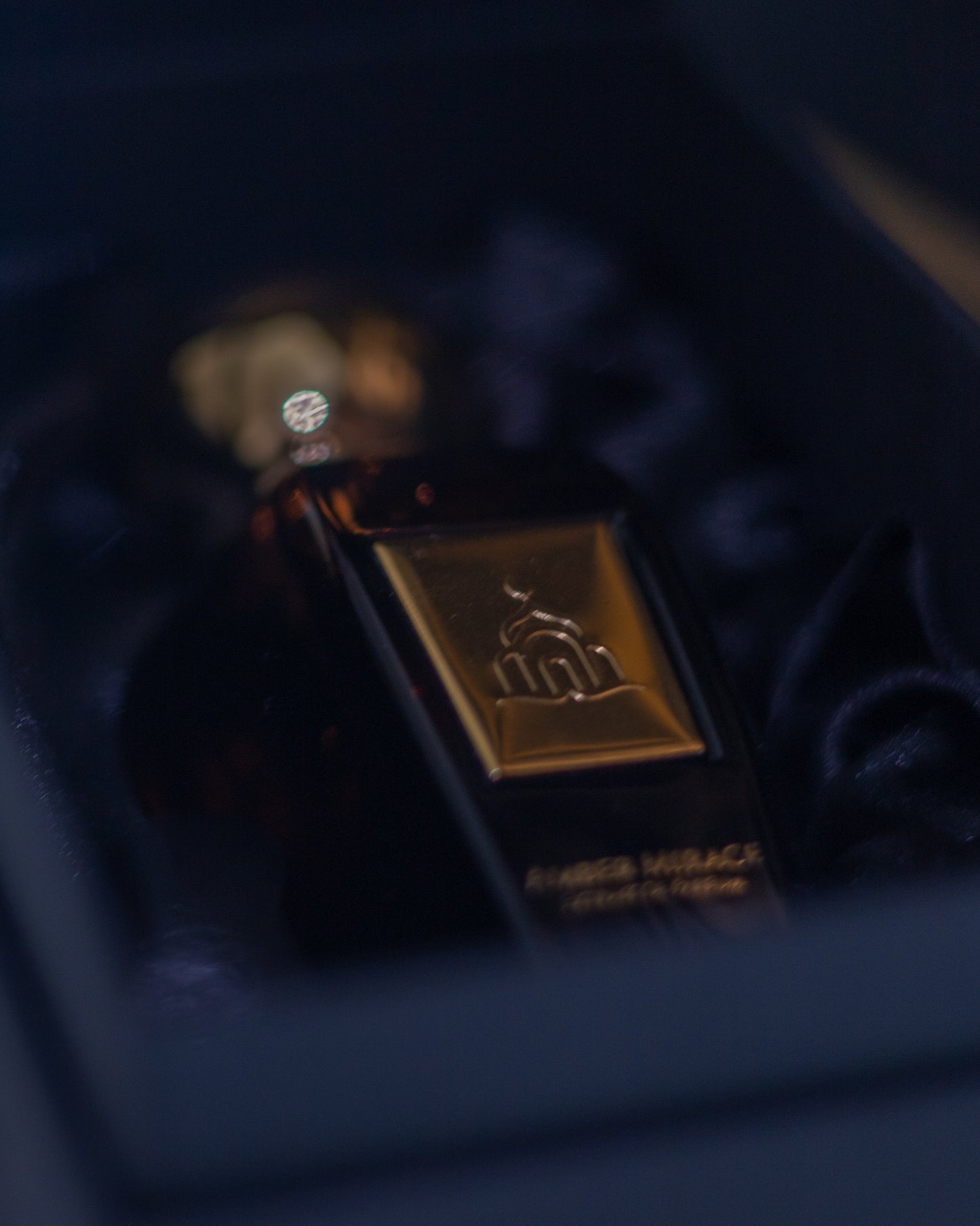 Close-up of a perfume bottle with a gold cap and label on a dark background