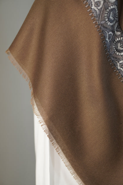 Brown fabric from shemagh with intricate patterned edge on a neutral background
