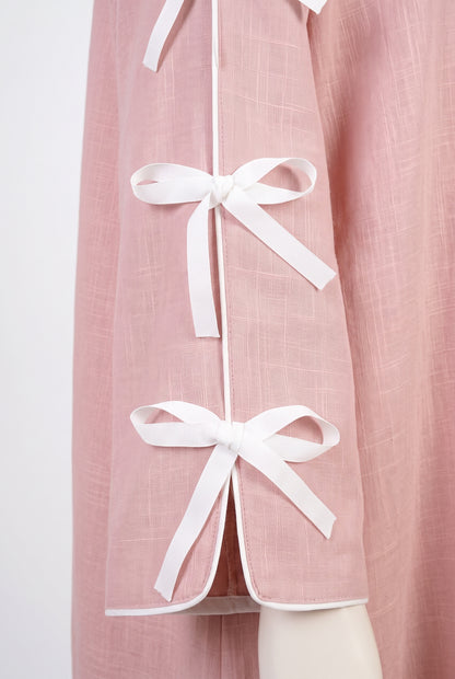 Close-up of the white ribbon bows on a pink open abaya sleeve