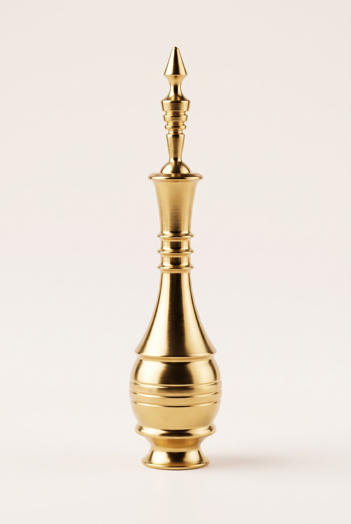 Golden Egyptian copper kohl applicator standing on a cream background