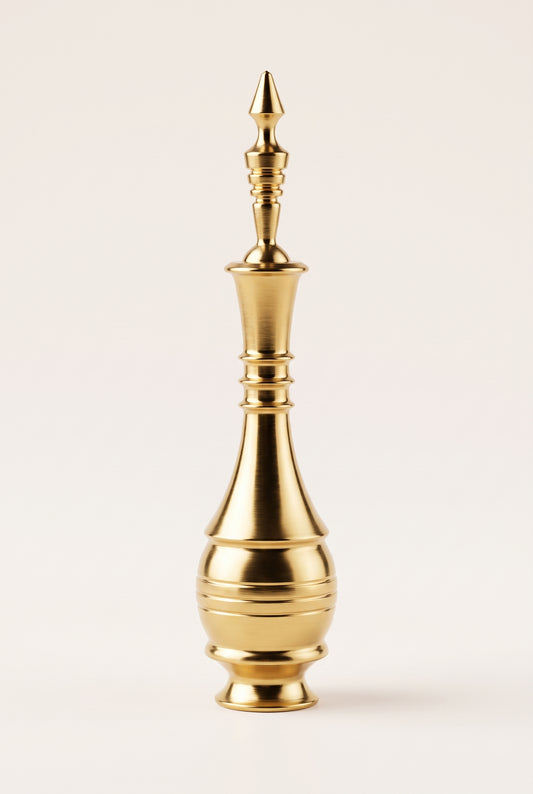 Golden Egyptian copper kohl applicator standing on a cream background