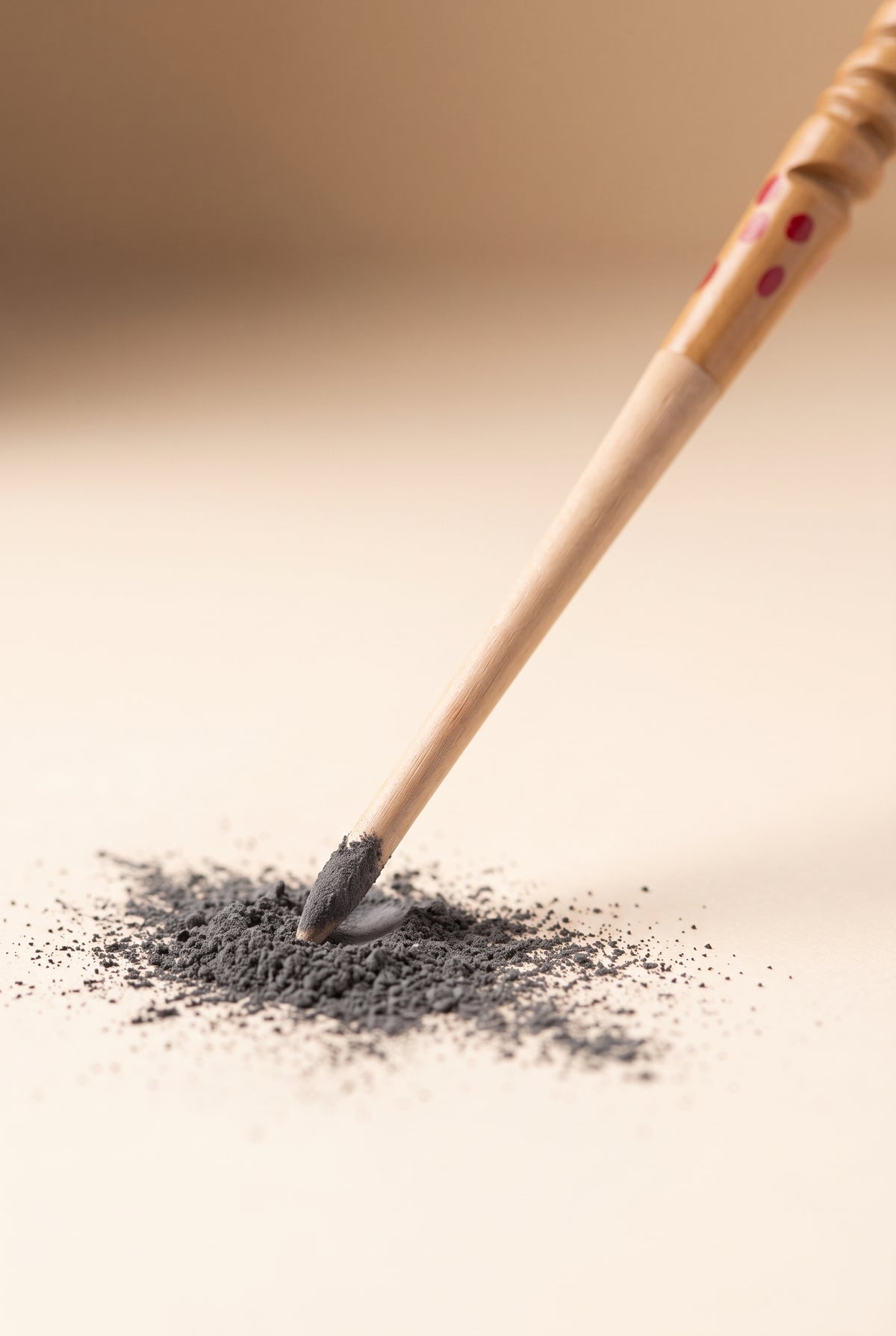 Close-up of a wooden kohl stick tip coated in charcoal kohl powder