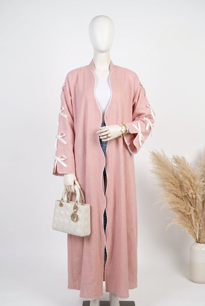 Pink open abaya with white ribbon bow sleeves on a mannequin