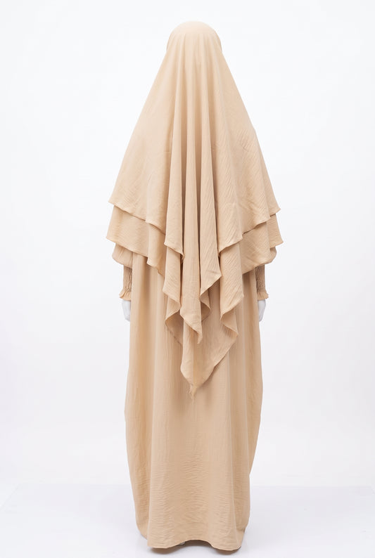 Beige 2-piece tiered khimar and abaya set with smocked cuffs on a mannequin