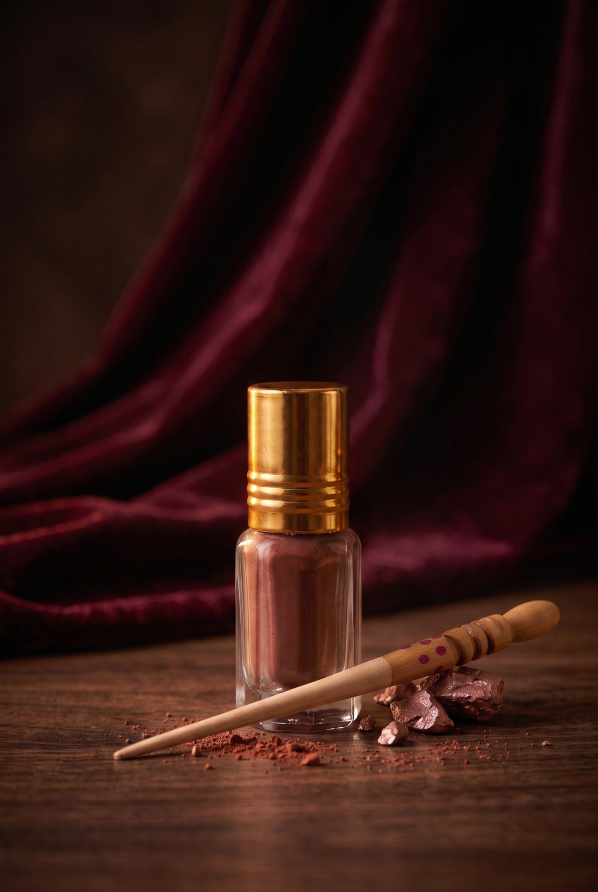 Red Ithmid Kohl bottle with traditional wooden kohl stick resting on raw red Ithmid stones