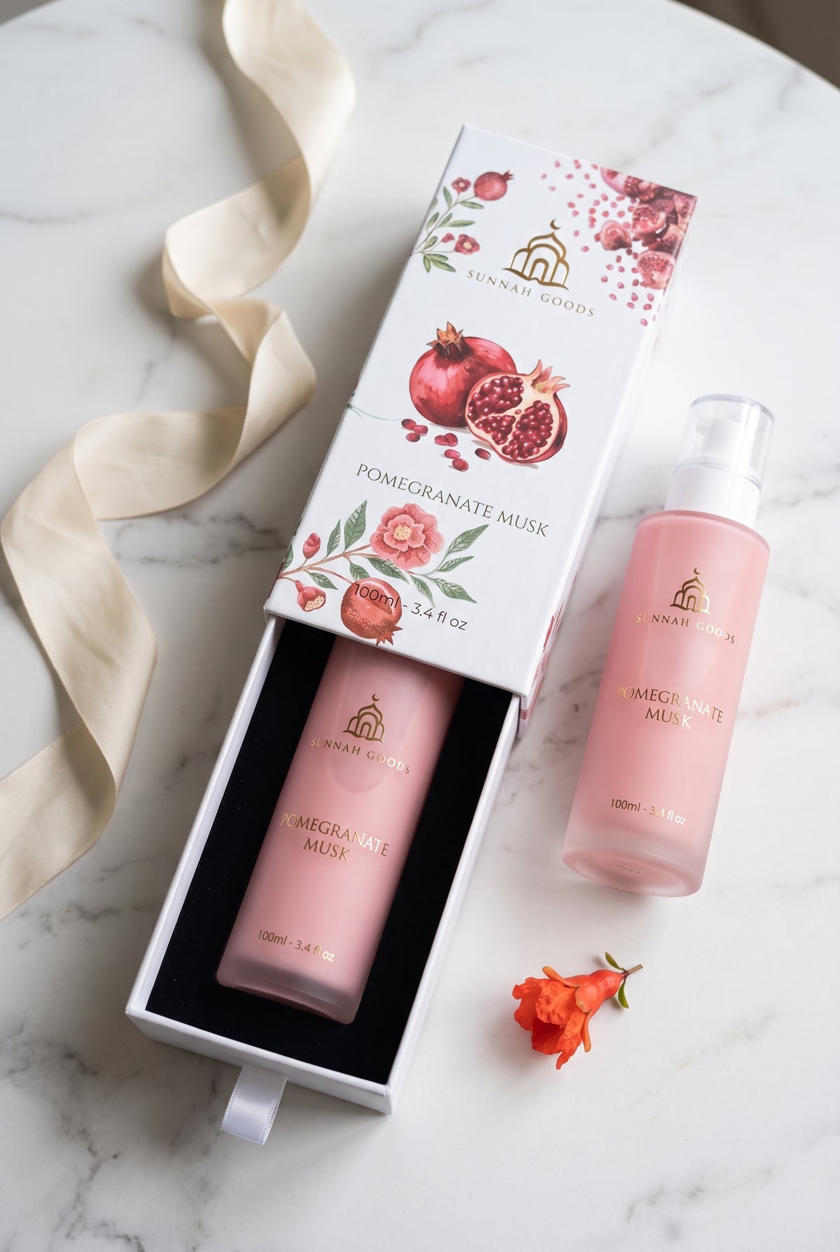 Musk Al Tahara Pomegranate Musk bottle in its slide-out gift box with ribbon pull, beside a second bottle