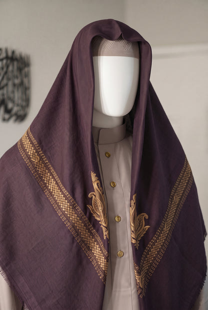 A dark purple shemagh with gold embroidered patterns and borders, draped over a mannequin wearing a light beige shirt.