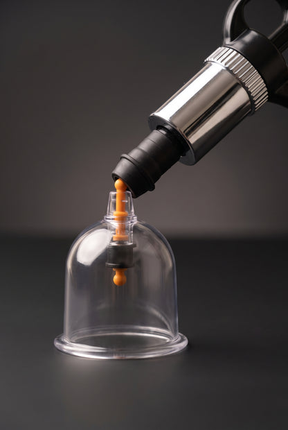 Hand pump nozzle attached to the orange valve of a clear hijama cup