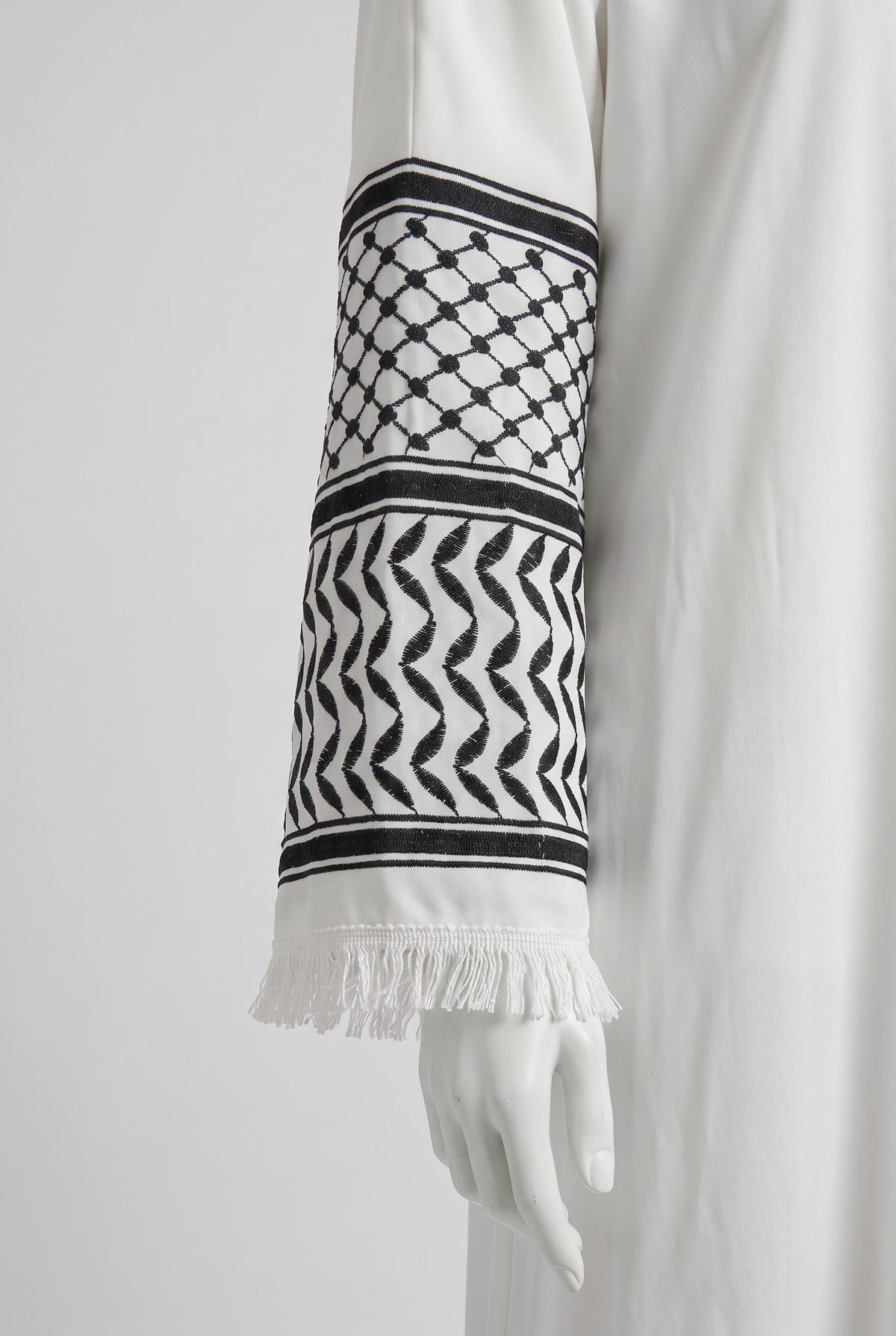 Close-up of the black and white keffiyeh pattern cuff on a white Palestine heritage abaya