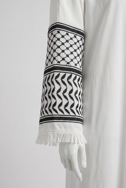 Close-up of the black and white keffiyeh pattern cuff on a white Palestine heritage abaya