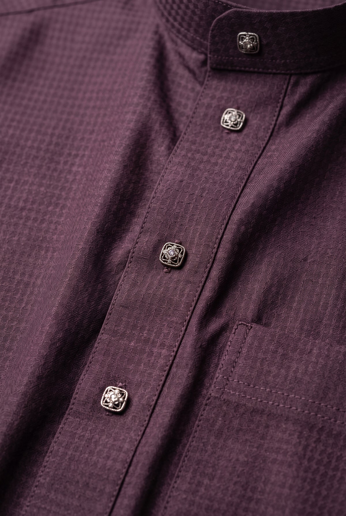Close-up of the textured burgundy fabric and buttons on an Al Aseel winter thobe
