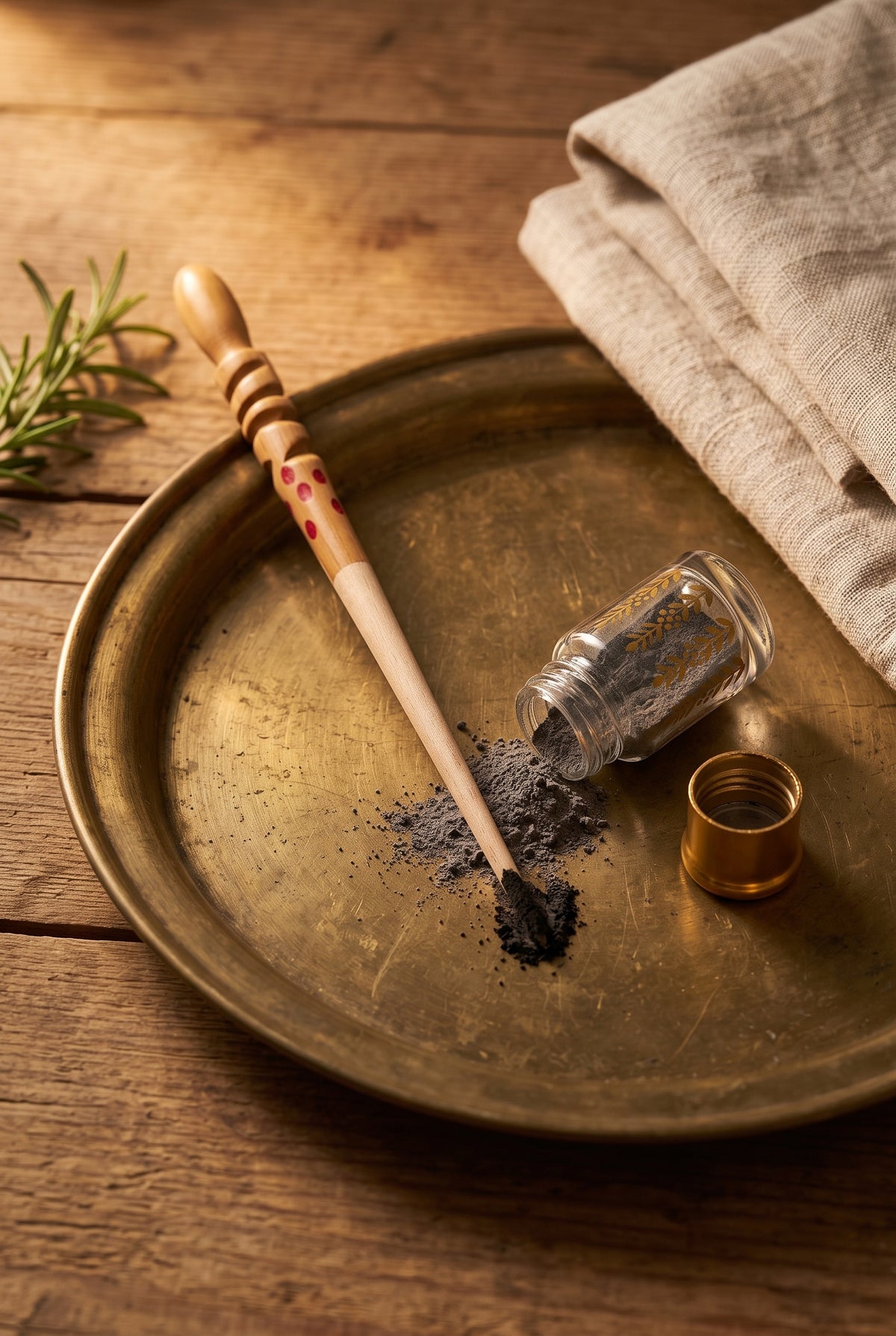 Wooden kohl stick resting on a brass tray beside an open bottle of kohl