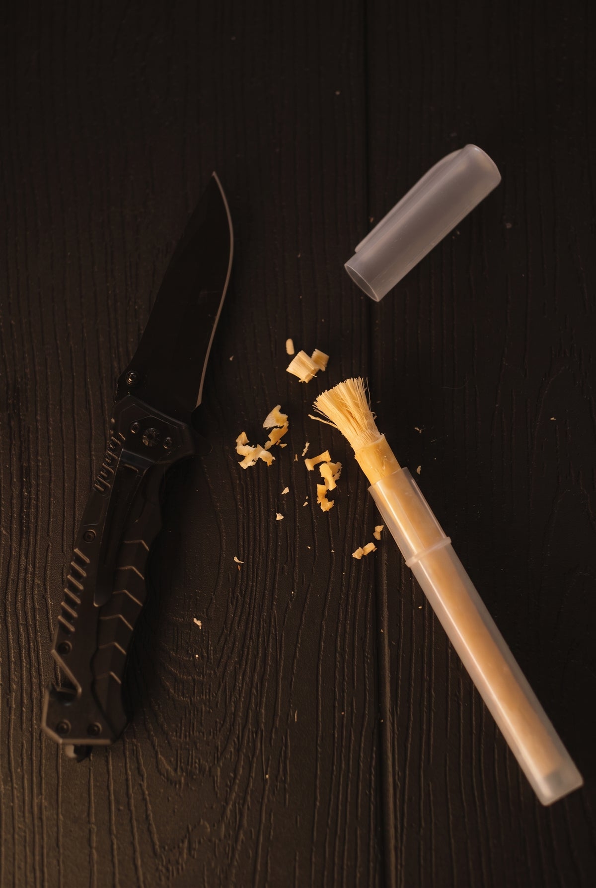 Arak miswak with a freshly peeled bristle tip, clear holder and wood shavings beside a folding knife