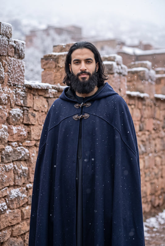 Man wearing a navy Arabian burnous hooded winter cloak in a snowy village