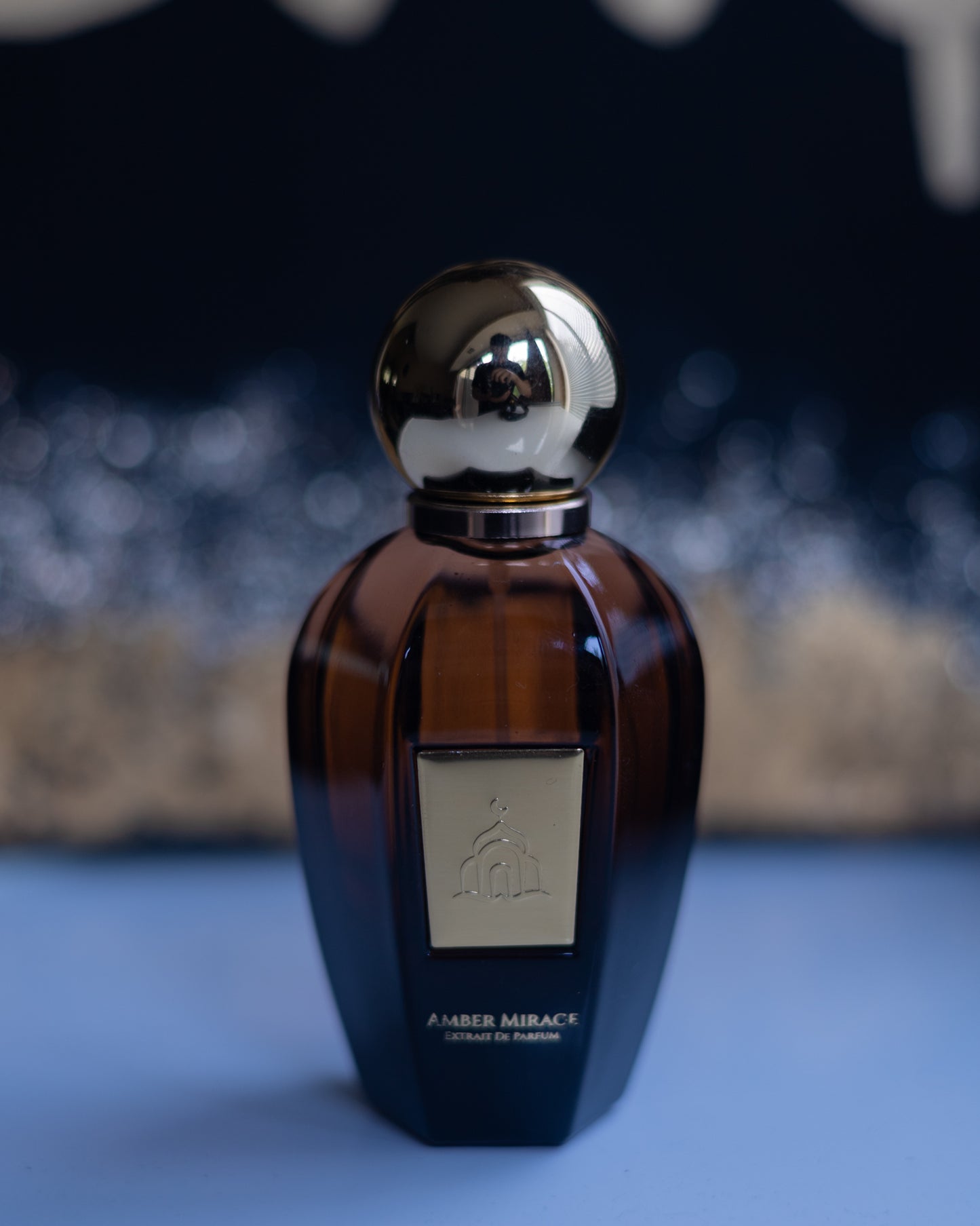 Perfume bottle with gold cap on a blue surface