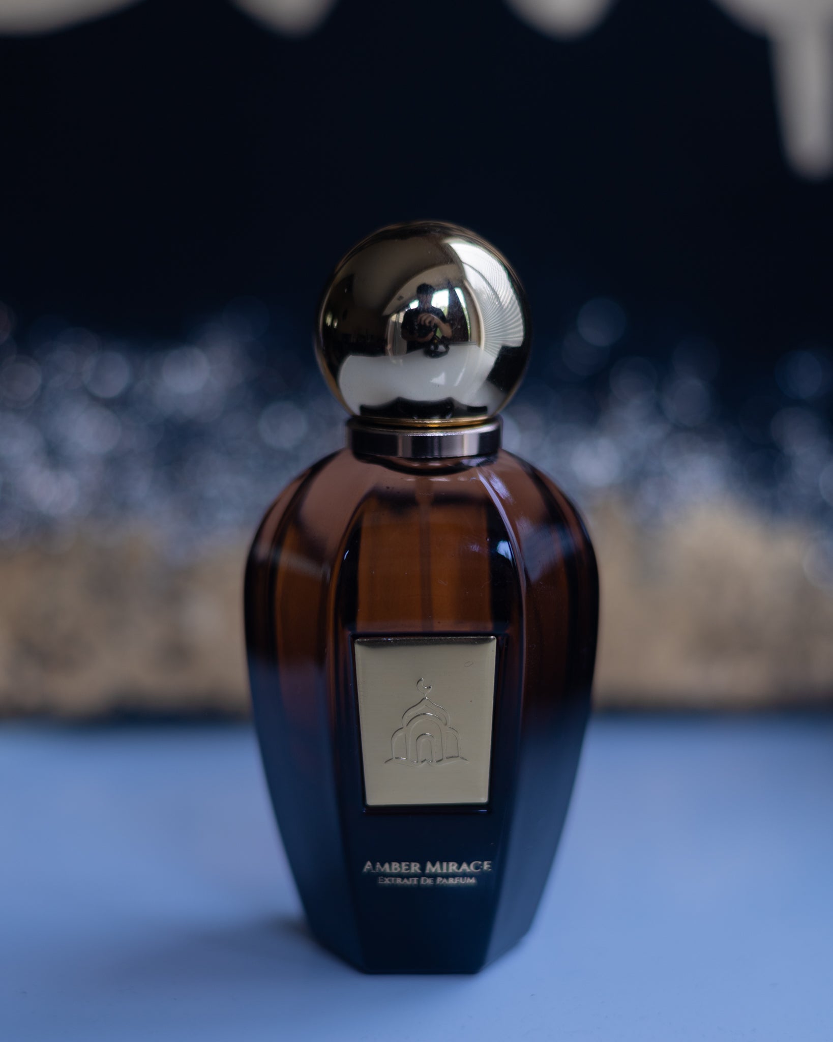 Perfume bottle with gold cap on a blue surface