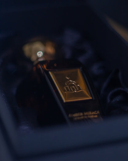Close-up of a perfume bottle with a gold cap and label on a dark background