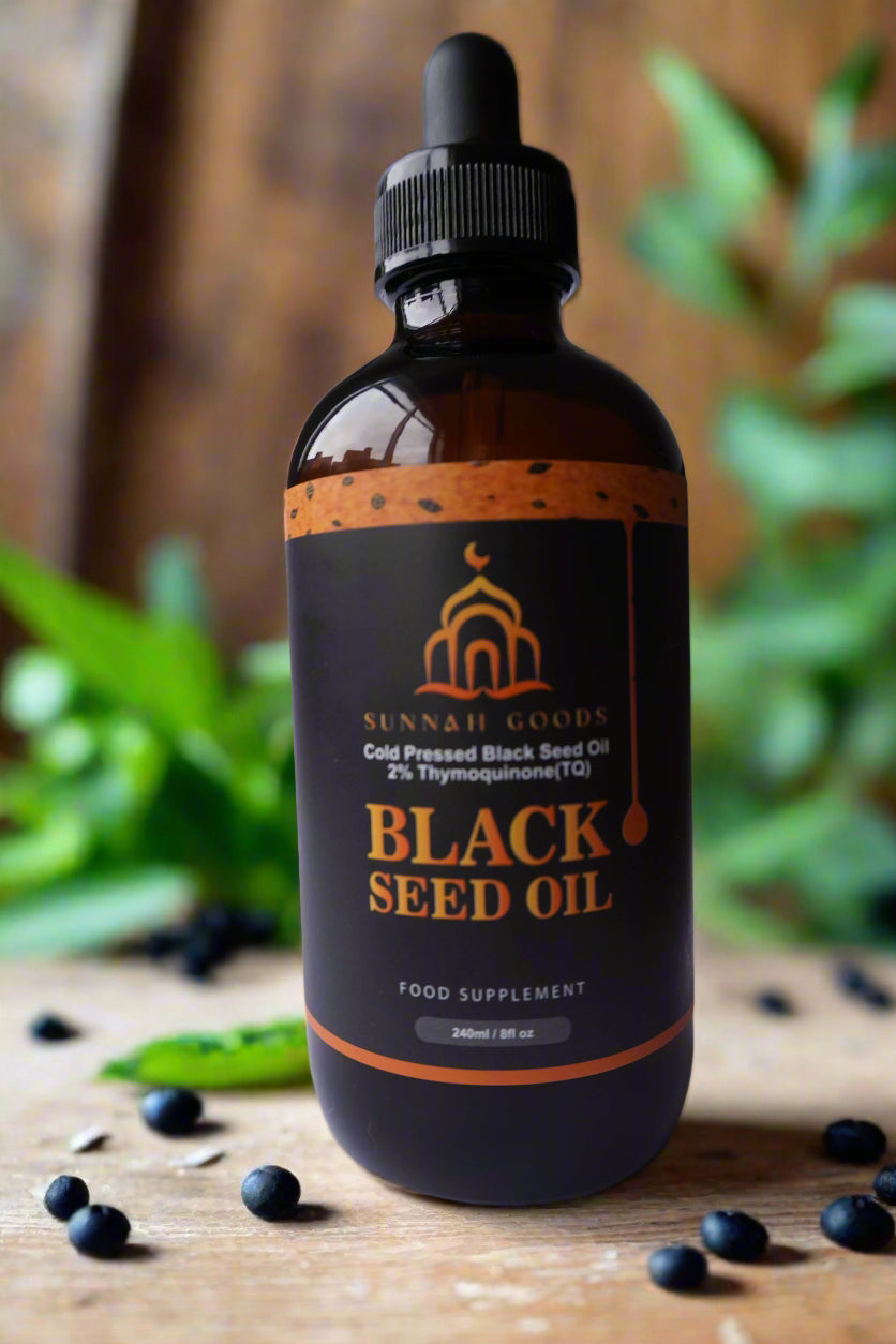 Close-up of black seed oil bottle and box on a dark countertop, with golden lighting highlighting its premium design